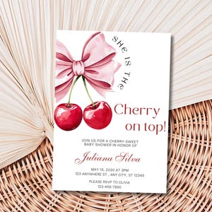 May include: A pink and white baby shower invitation with a watercolor illustration of two red cherries and a pink bow. The text reads "She is the Cherry on top!" and includes the details of the event, including the date, time, location, and RSVP information.