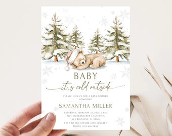 May include: Baby shower invitation featuring a watercolor illustration of a sleeping teddy bear in a winter scene with pine trees and snowflakes. The text reads "Baby it's cold outside" and includes event details.