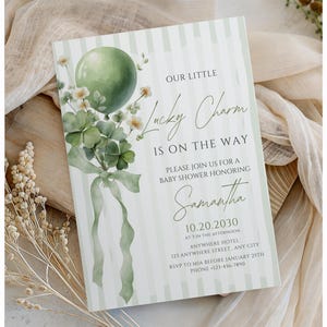 May include: Baby shower invitation with a green balloon, shamrocks, and floral accents. The invitation reads "Our Little Lucky Charm Is On The Way" and includes details for a baby shower honoring Samantha.