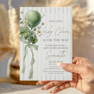 May include: Baby shower invitation with a green balloon, shamrocks, and the text "Lucky Charm is on the Way." The invitation is light green with vertical stripes and features the name "Samantha" and event details.