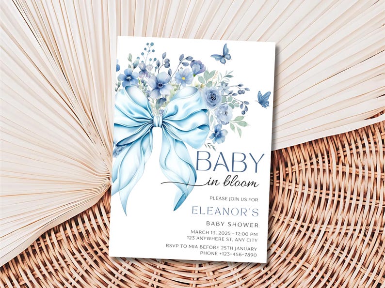 May include: Blue and white baby shower invitation with a watercolor illustration of a blue bow and flowers. The text reads "Baby in Bloom" and "Eleanor's Baby Shower".