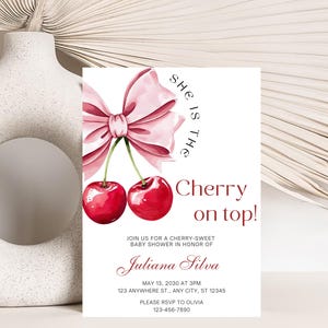 May include: A pink and white baby shower invitation with a cherry and bow illustration. The text reads "She is the Cherry on top!" and includes the name "Juliana Silva" and the date "May 13, 2030 at 3PM".