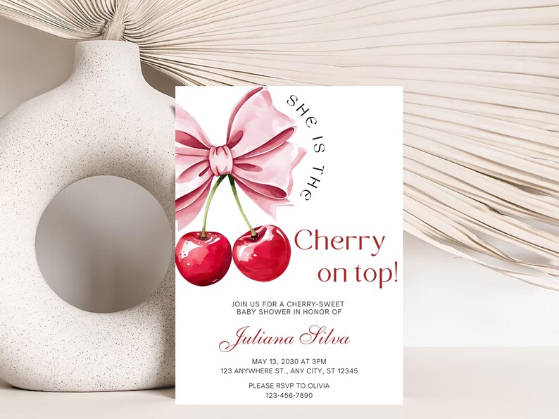 May include: A pink and white baby shower invitation with a cherry and bow illustration. The text reads "She is the Cherry on top!" and includes the name "Juliana Silva" and the date "May 13, 2030 at 3PM".