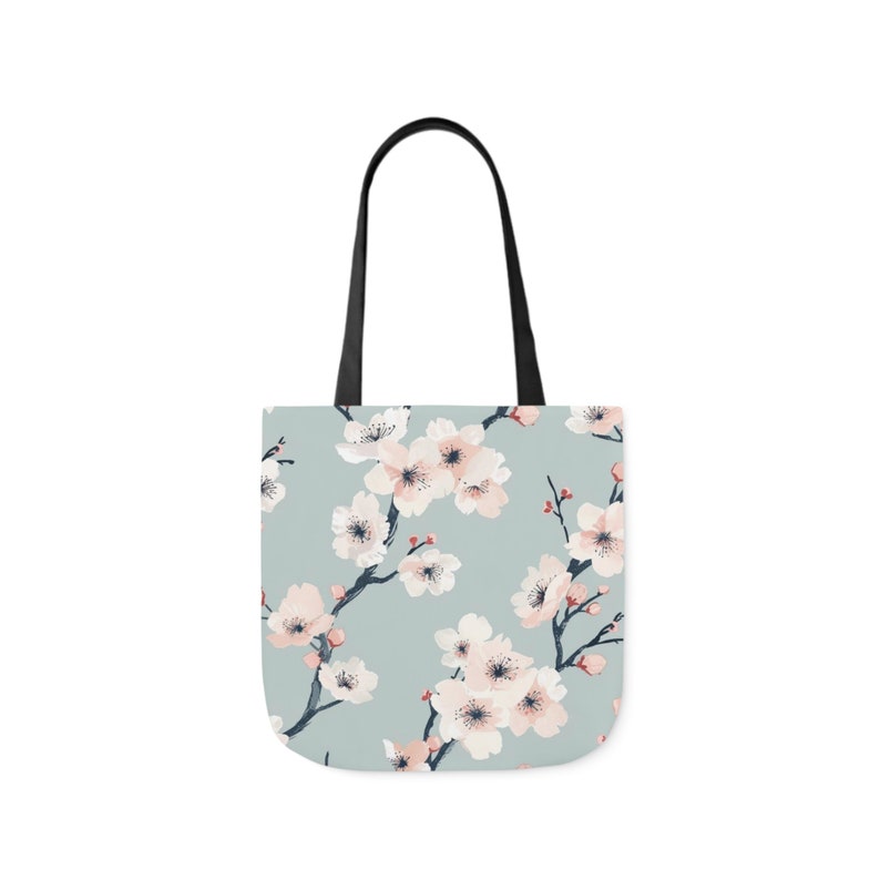 Elegant canvas tote bag with a serene cherry blossom print in pastel shades on a soft blue background, combining style and practicality for everyday use.