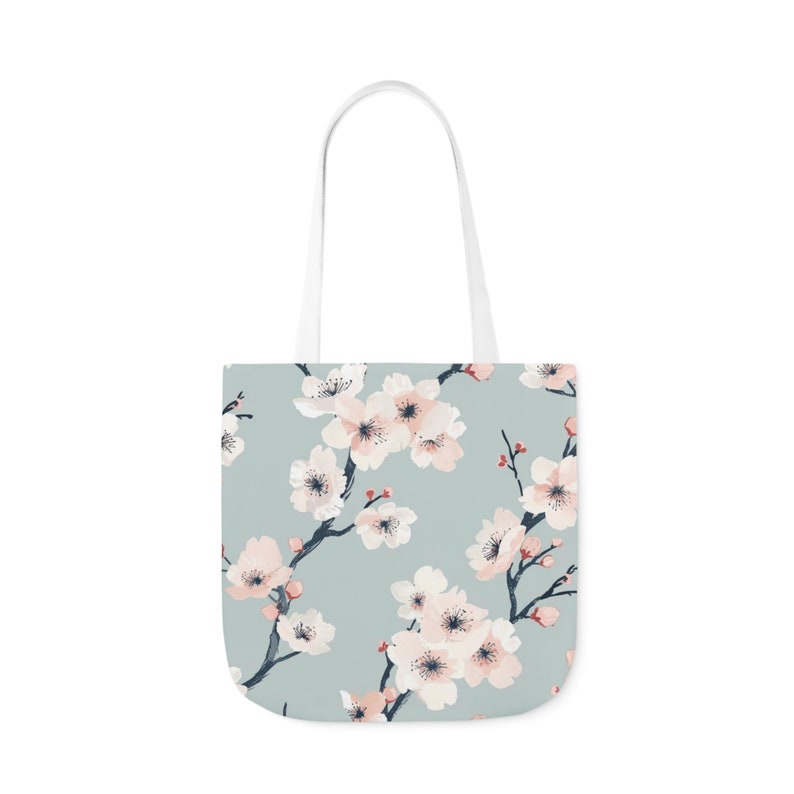 Elegant canvas tote bag with a serene cherry blossom print in pastel shades on a soft blue background, combining style and practicality for everyday use.