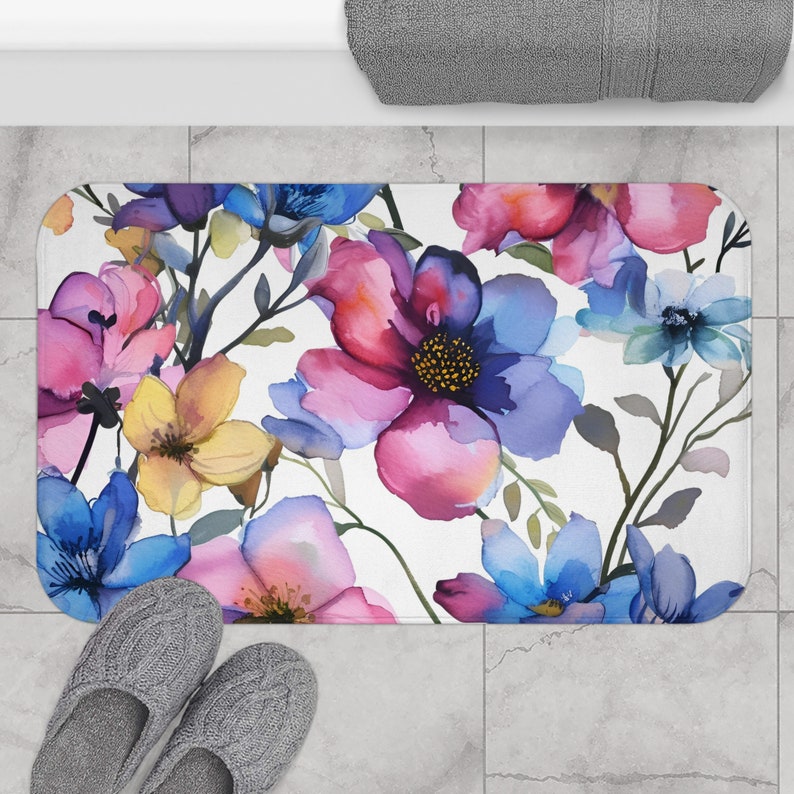 A foam bath mat featuring a lush watercolor painting of vibrant flowers in shades of pink, blue, and yellow, offering a stylish and comfortable addition to bathroom decor.