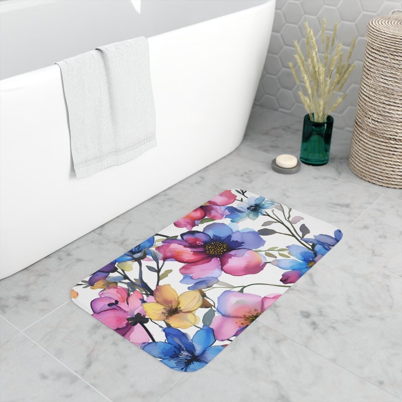 A foam bath mat featuring a lush watercolor painting of vibrant flowers in shades of pink, blue, and yellow, offering a stylish and comfortable addition to bathroom decor.