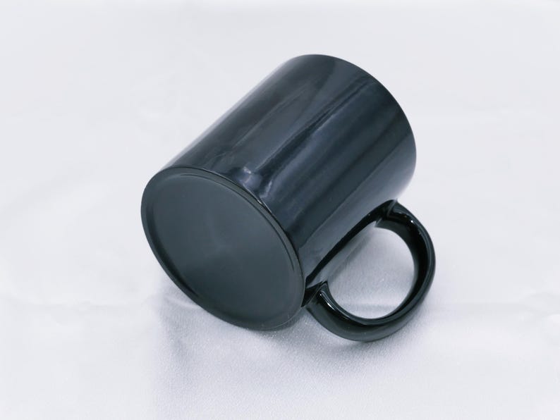 May include: A black ceramic mug with a glossy finish. The mug has a cylindrical shape with a rounded handle. The mug is designed for hot or cold beverages and is suitable for home or office use.