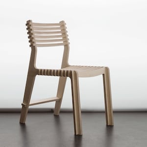 Peut inclure: Une chaise en bois clair avec un dossier et un siège à lattes. La chaise a un design simple et moderne.