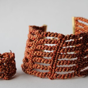 May include: A set of two crocheted jewelry pieces in a rust orange color. The set includes a bracelet and a ring.