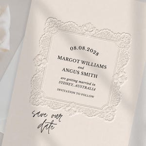 May include: A cream-colored save the date card featuring an embossed lace-style border and black text that reads 08.08.2028, MARGOT WILLIAMS and ANGUS SMITH are getting married in SYDNEY, AUSTRALIA, INVITATION TO FOLLOW, and save our date.