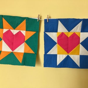 Peut inclure: Deux carrés de tissu avec un motif d'étoile et un cœur au centre. Le carré de gauche a un fond vert avec des accents orange et blanc. Le carré de droite a un fond bleu avec des accents blancs et jaunes. Les deux cœurs sont roses.