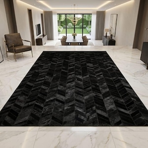 May include: A large rectangular area rug featuring a dark black chevron pattern. The rug is composed of individual rectangular panels arranged in a repeating V-shaped design, creating a textured surface that covers the floor in a spacious room.