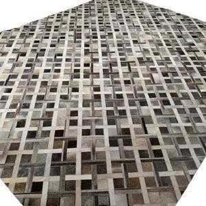 May include: A large, rectangular rug with a woven pattern. The rug features a patchwork design of squares and rectangles in shades of brown, gray, and cream. The texture appears to be soft and inviting, suitable for a living room or bedroom.
