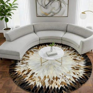 May include: A large, curved, light gray sofa with a rounded back and seat cushions. In front of the sofa sits a round white marble coffee table with thin gold legs. Beneath the table is a large circular rug featuring a geometric diamond pattern.