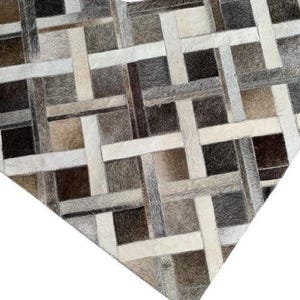 May include: A geometric rug with a patchwork design. The rug features a pattern of intersecting rectangles in shades of brown, gray, and cream. The texture appears to be soft and the rug is likely made of natural materials.