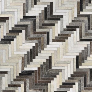 May include: A rectangular rug featuring a repeating herringbone pattern composed of individual strips of cowhide. The surface displays a neutral colour palette of white, cream, beige, grey, brown, and black, with visible stitching between each piece.