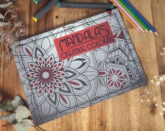 May include: A coloring book with a red, white, and black mandala design on the cover. The title of the book is "MANDALAS CREATIVE COLORING".