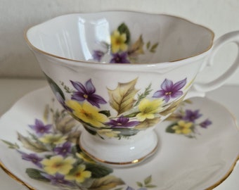 Taza de té y platillo Royal Albert con flores amarillas y moradas.