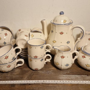 May include: A set of white ceramic teacups and saucers with blue and red floral designs. The set includes a teapot, creamer, sugar bowl, and six cups and saucers.