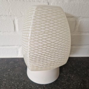 May include: A vintage white and clear glass light fixture with a geometric pattern. The light fixture has a rounded, rectangular shape with a white base. The clear glass shade features a diamond-shaped pattern.