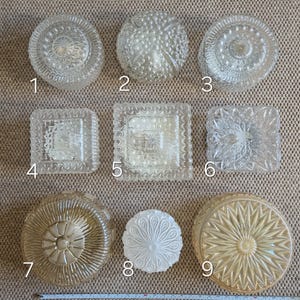 May include: Nine vintage glass light shades in various shapes, including round and square. The shades display embossed patterns like floral, geometric, and bubble designs. Some are clear, others frosted or amber-tinted. A measuring tape is at the bottom, showing the size in centimetres.