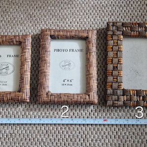 May include: Three woven rectangular photo frames in varying shades of brown. The frames are labeled with sizes, including a 4" x 6" (10 x 15cm) frame. The frames are arranged on a textured surface with a measuring tape.