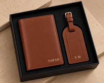 May include: A brown textured passport holder and a matching luggage tag with a gold buckle, presented in a black gift box. The passport holder is embossed with the name SARAH, and the luggage tag features the initials S M in gold lettering.