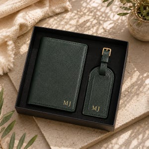 May include: A dark green passport holder and a matching luggage tag set presented in a black gift box. Both items feature a textured finish and are personalized with the gold-colored initials MJ embossed on the front of each piece.