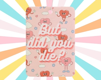 May include: Rectangular air freshener with a pink background featuring cartoon hearts and the text "But did you die?". The hearts have arms, legs, and various expressions. The air freshener has a string for hanging.