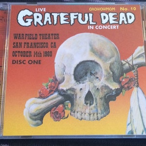 May include: CD case for the Grateful Dead's "Live" concert at the Warfield Theater in San Francisco, CA, on October 14th, 1980. The cover features a skull with a bone, roses, and the text "OXOWOWMOM No. 10".