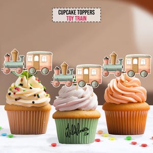 May include: Three cupcake toppers featuring a toy train with a blue engine and a pink boxcar. The toppers are on top of cupcakes with white, pink, and tan frosting.
