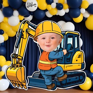 Op de afbeelding: Uitgesneden afbeelding van een baby met een gele bouwhelm en een oranje vest, geposeerd met een gele en blauwe graafmachine. De achtergrond heeft een ballonnenboog in marineblauw, geel en wit. De ballonnenboog heeft de tekst "Wildflower .co" op een witte ballon.