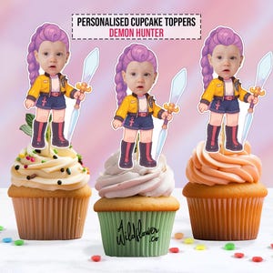 May include: Three cupcakes topped with personalized Demon Hunter cake toppers. Each topper features a cartoon image of a child with purple hair, a yellow jacket, and a sword. The cupcakes have different frosting colors and are decorated with sprinkles.