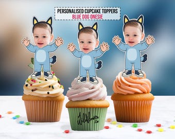 May include: Three cupcakes topped with personalized Blue Dog Onesie toppers. Each topper features a child in a blue onesie with a dog tail and ears. The cupcakes have different frosting colors and are decorated with sprinkles.