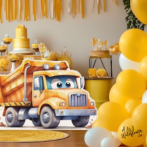 May include: A yellow cartoon dump truck with a smiling face. The truck is on a white background with a yellow rug in the foreground. There are yellow and white balloons in the background.