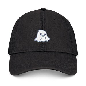 May include: Black baseball cap with a white embroidered ghost design on the front. The ghost has blue eyes and a friendly expression. The cap has a curved brim and an adjustable strap.