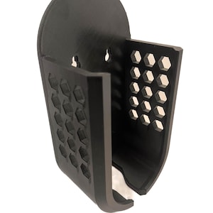 May include: A black plastic wall mount with a honeycomb pattern and two holes for mounting.