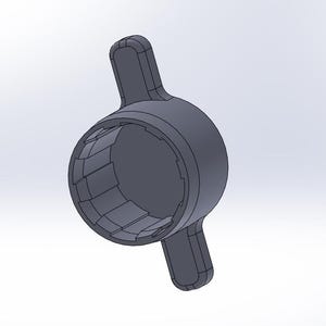 Puede incluir: Un tapón de botella de plástico gris con dos alas a cada lado. El tapón tiene un diseño texturizado y acanalado alrededor de la abertura.