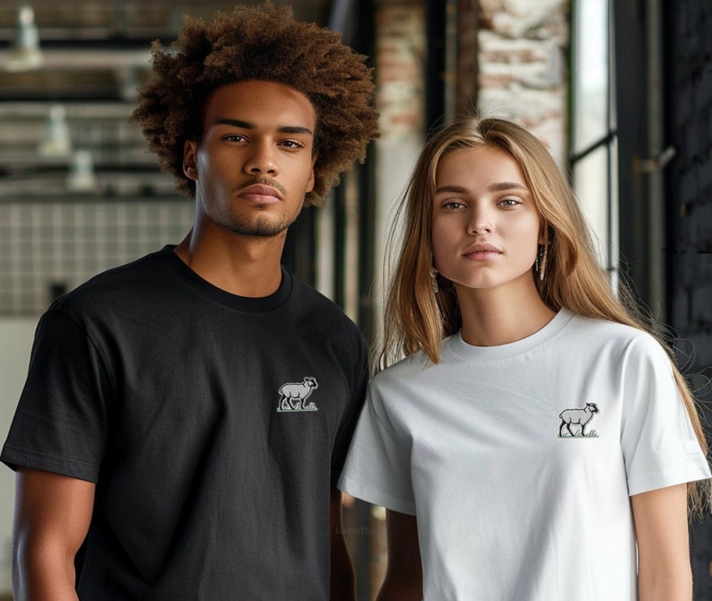 May include: Two people wearing t-shirts with a small embroidered sheep design. The person on the left is wearing a black t-shirt and the person on the right is wearing a white t-shirt.