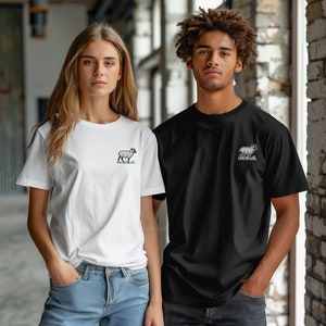 May include: Two people wearing t-shirts with a small embroidered image of a sheep on the front. The person on the left is wearing a white t-shirt and the person on the right is wearing a black t-shirt.