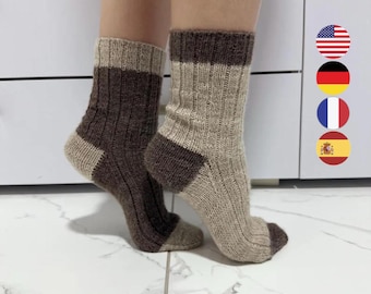 May include: A pair of ribbed knit socks featuring a color-blocked design. One sock is primarily dark brown with a light beige cuff and heel, while the other is light beige with a dark brown cuff, heel, and toe section, crafted in a wool-like texture.