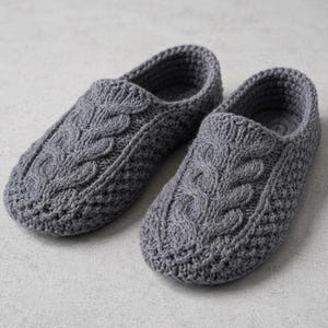 Peut inclure: Une paire de chaussons gris au crochet présentant un motif central en torsade sur le dessus du pied, entouré d'un point texturé. Les chaussons ont un bout arrondi et une ouverture basse pour faciliter l'enfilage.