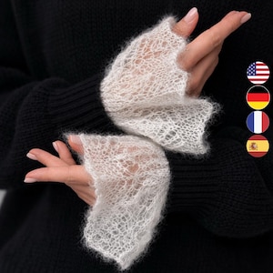 May include: Delicate white lace fingerless gloves with flared cuffs. The gloves are made of a sheer, open-weave material, offering a touch of elegance. The gloves are set against a black background, highlighting the intricate details of the lace.
