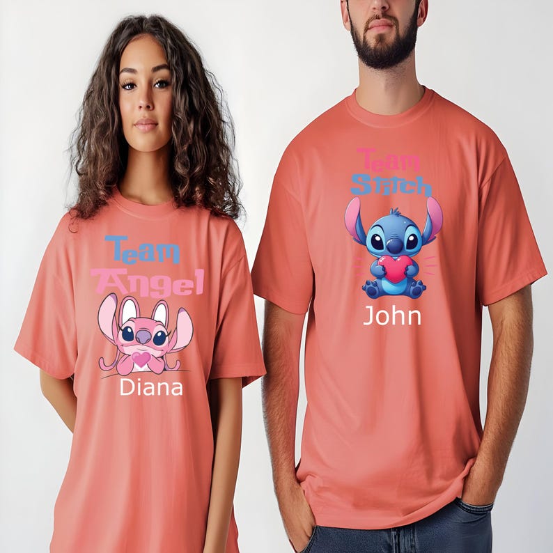 Puede incluir: Dos camisetas color coral con personajes de dibujos animados. Una muestra "Team Angel" y "Diana", con un personaje rosa. La otra muestra "Team Stitch" y "John", con un personaje azul sosteniendo un coraz&oacute;n. Para parejas.