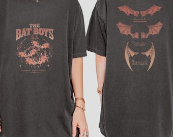 May include: Black oversized t-shirt with a graphic print of bats and the text "The Bat Boys" on the front. The back of the shirt features three different types of bat wings with the text "Ariel", "Cassiopeia", and "Nyx" underneath each.