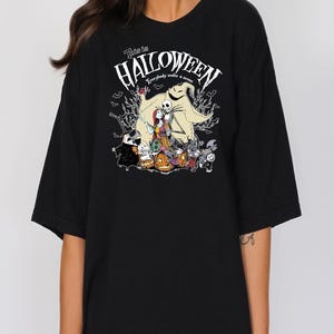 Op de afbeelding: Zwart T-shirt met een afbeelding uit "The Nightmare Before Christmas". Het ontwerp bevat Jack Skellington, Sally en andere personages met de tekst "This is Halloween". Een griezelig ontwerp voor fans van de film.