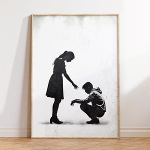 Può includere: Stampa in silhouette in bianco e nero di una donna che offre la mano a un uomo inginocchiato a terra. La stampa ha uno sfondo testurizzato.