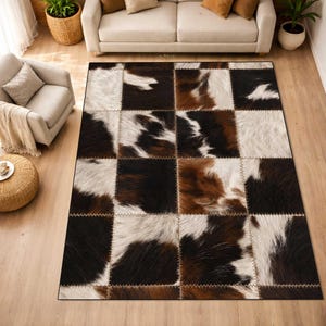 May include: A large, rectangular area rug with a patchwork design. The rug features squares of faux cowhide in shades of brown, black, and white. The squares are stitched together with a light brown thread, creating a rustic and textured appearance.