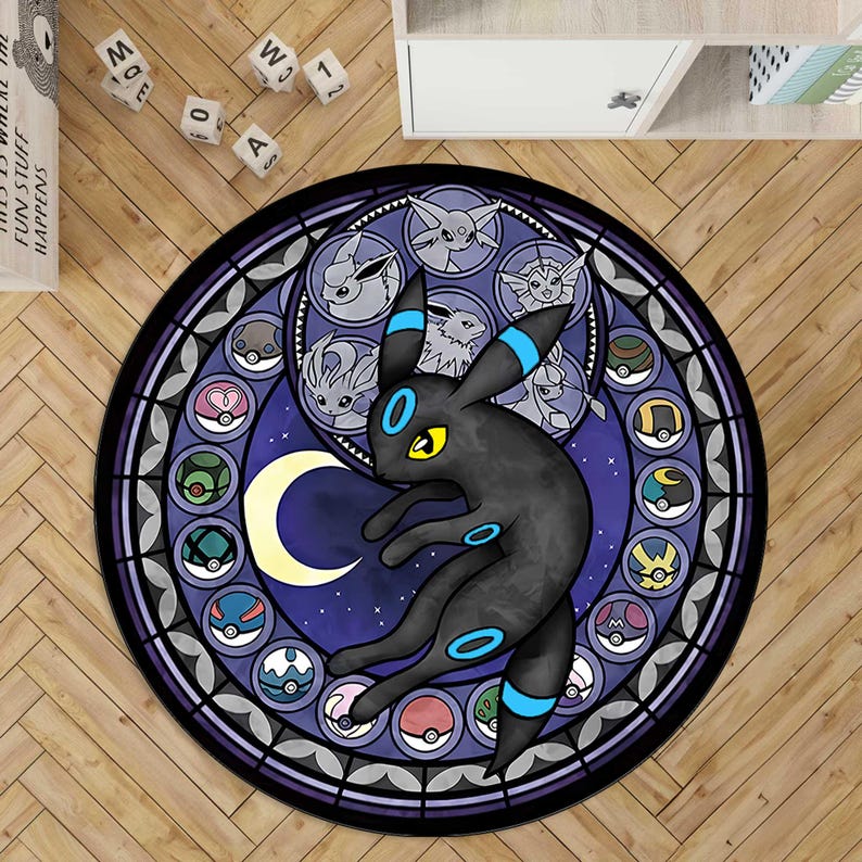 Op de afbeelding: Een rond vloerkleed met een ontwerp in glas-in-loodstijl, voorzien van een centraal zwart Umbreon-personage, een gele maansikkel en een omlijstende rand met diverse cirkelvormige iconen van Eevee-evoluties en kleurrijke bolvormige containers.